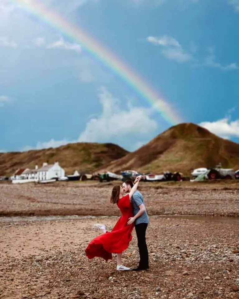 Smartphone travel photo of a couple kissing under a rainbow