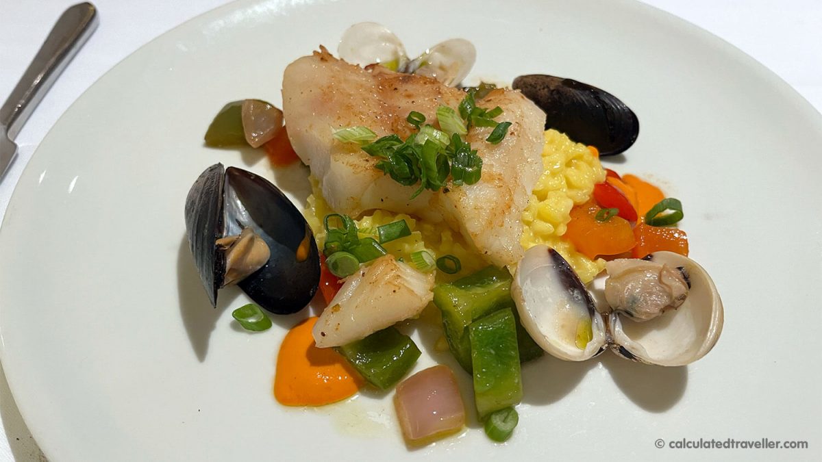 Pan-seared cod fish with saffron risotto, mussels, clams, peppers